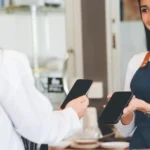 o que é nfc - Cliente satisfeita efetuando pagamento por celular utilizando tecnologia nfc