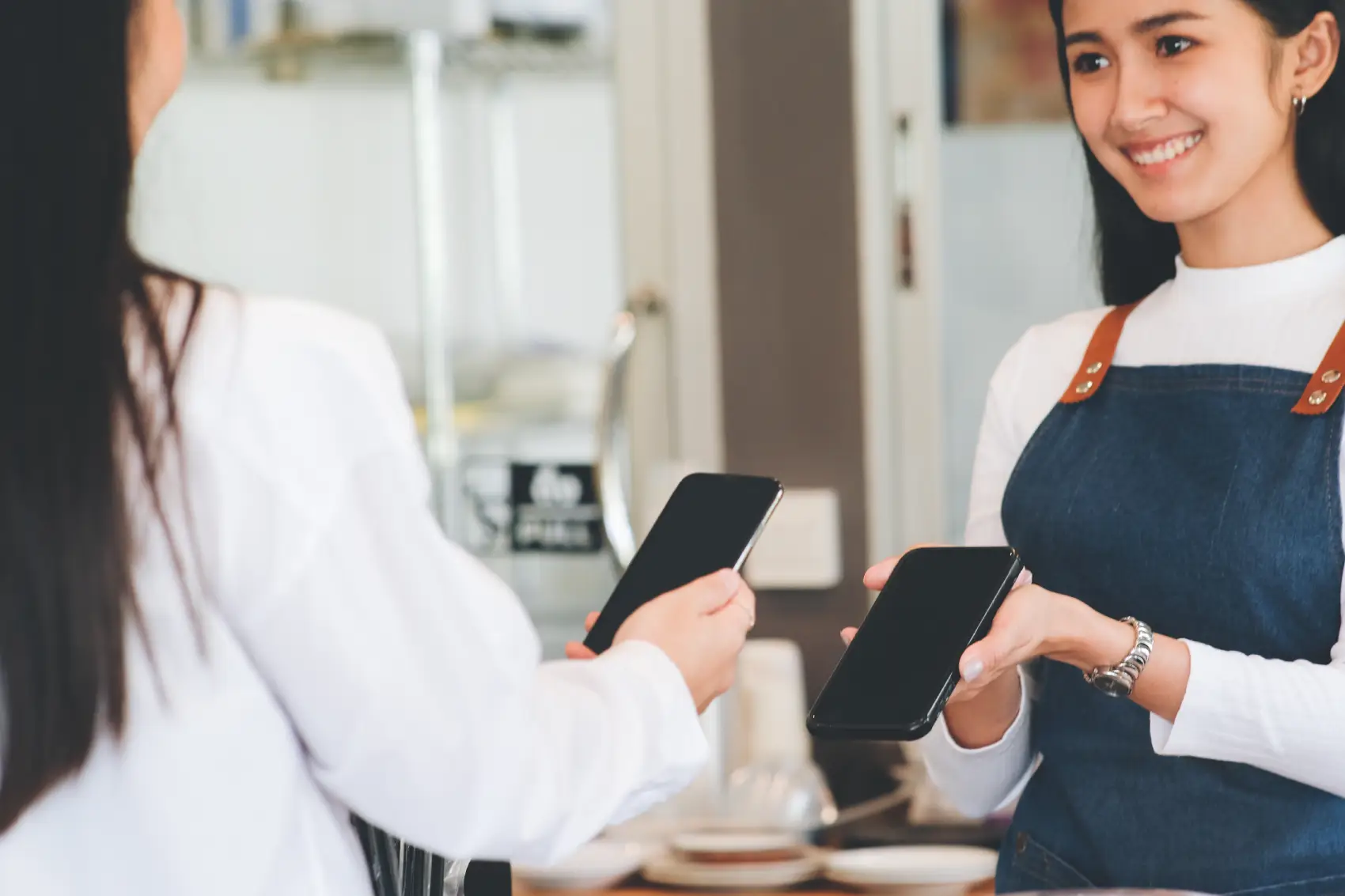 o que é nfc - Cliente satisfeita efetuando pagamento por celular utilizando tecnologia nfc