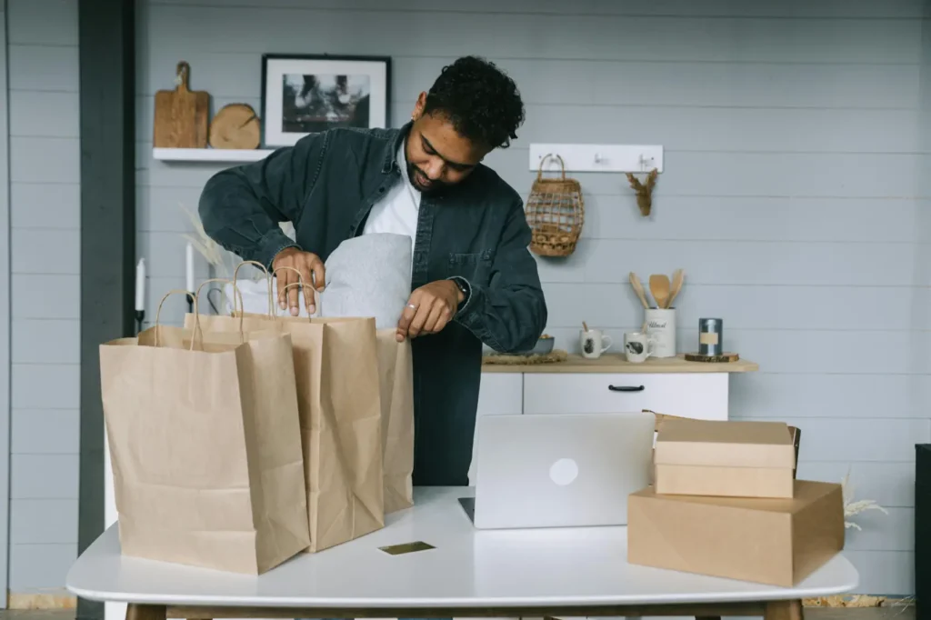 como-aumentar-as-vendas homem com sacolas e caixas e notebook aberto para vendas online