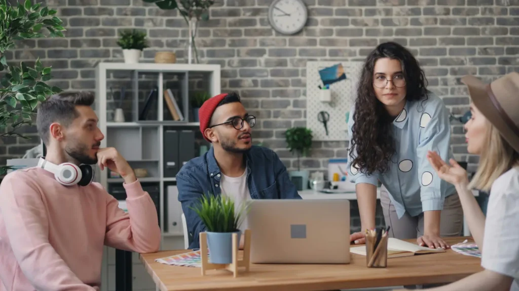 jovens-empreendedores reunidos em uma mesa de escritório compartilhando ideias com um notebook aberto