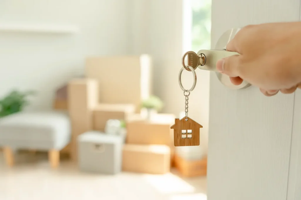 seguro residencial - chave com chaveiro em formato de casa em porta entreaberta de sala de estar
