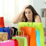 arrependimento de compra - mulher surpresa olhando para várias compras em sacolas coloridas em casa