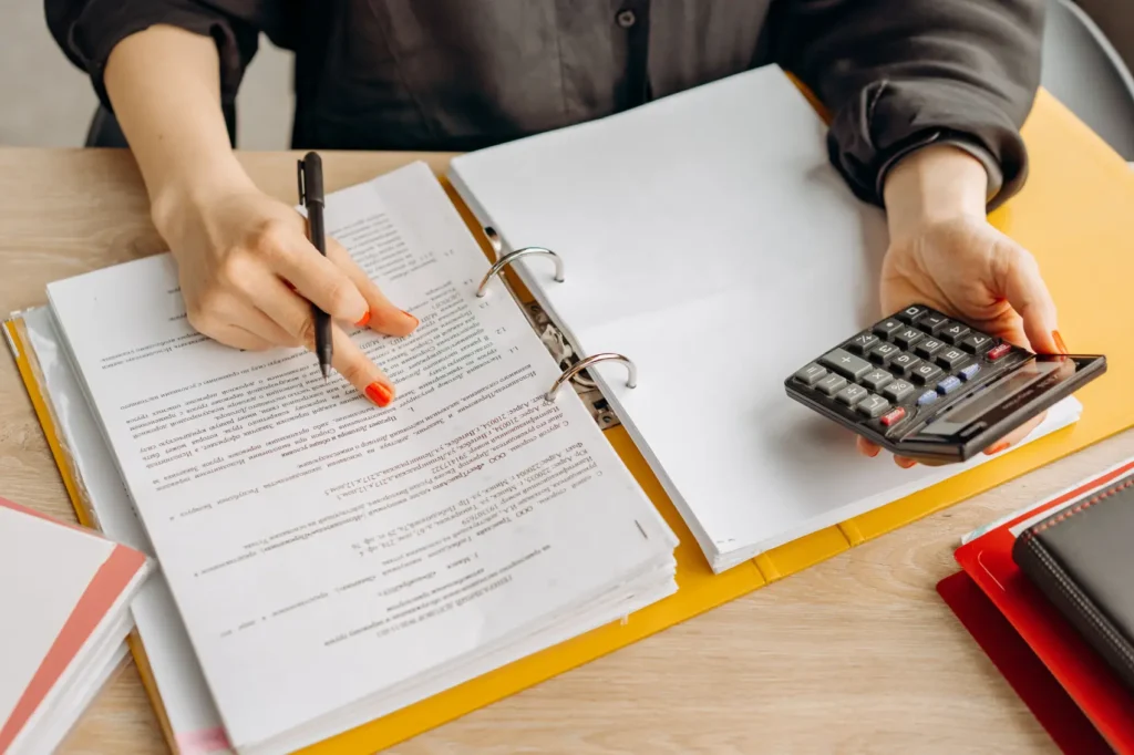 proposta-comercial pessoa com fichário e calculadora em mesa de escritório