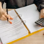 proposta-comercial pessoa com fichário e calculadora em mesa de escritório