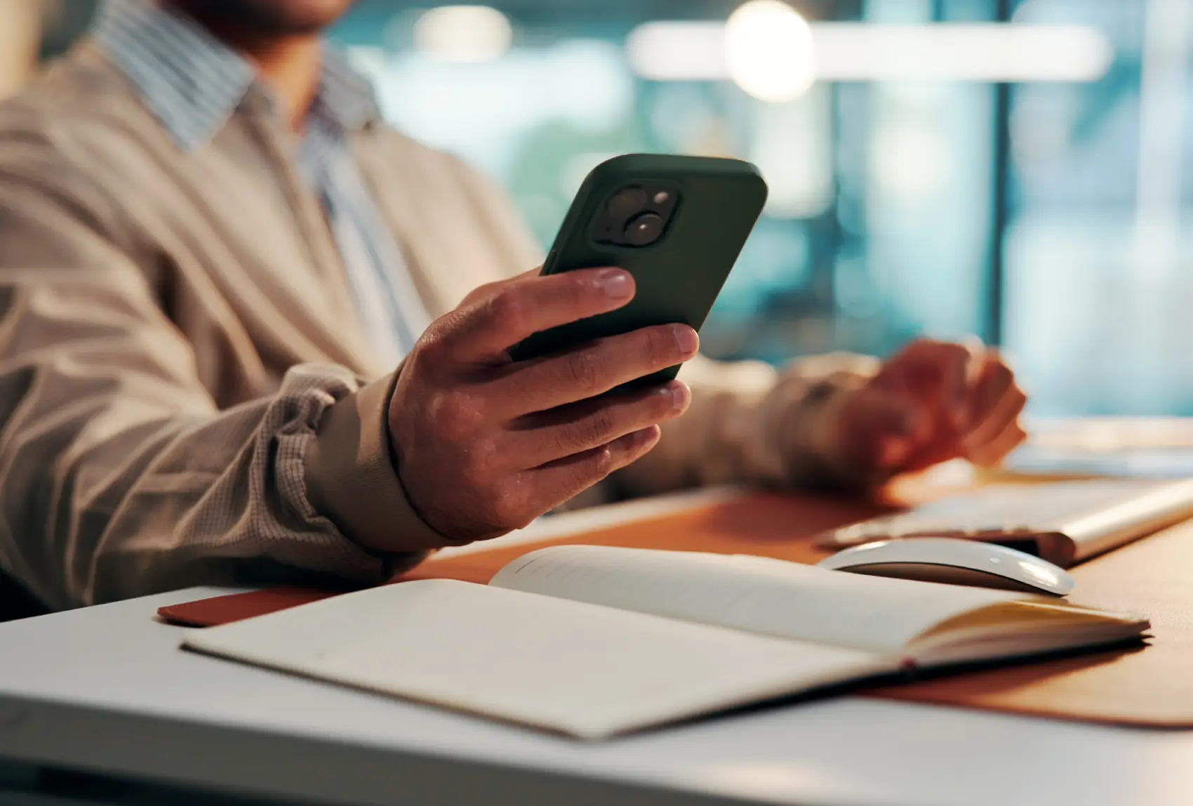 o que é ETF - mãos de homem de negócios olhando o celular com caderno aberto sobre a mesa