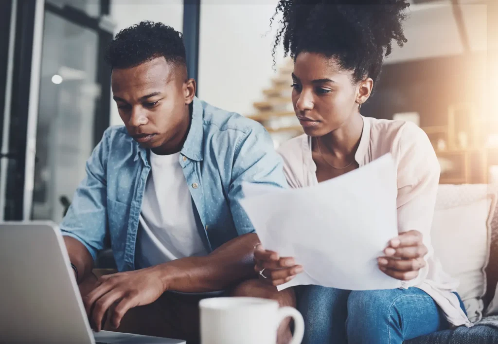 Antecipação FGTS - Casal negro em frente ao notebook com papéis nas mãos