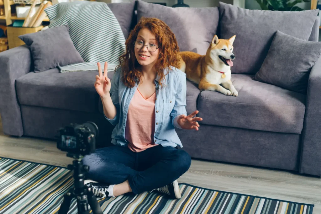 como-fazer-renda-extra mulher gravando com câmera e cachorro sentado no sofá