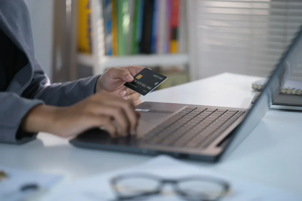 como comprar na black friday - mãos segurando um cartão de crédito na frente de um laptop
