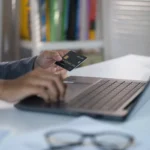 como comprar na black friday - mãos segurando um cartão de crédito na frente de um laptop