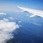 como comprar passagem aérea barata - A asa de um avião de passageiros durante o voo contra um céu azul com nuvens