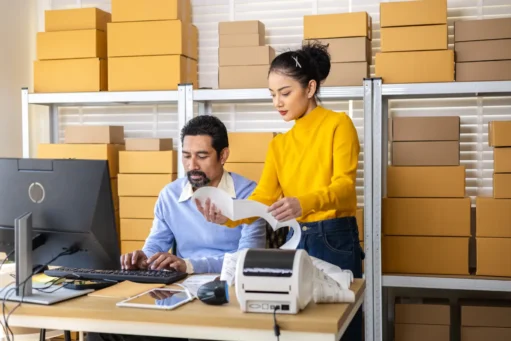 como-funciona-o-sedex casal olhando etiqueta e verificando pedidos com as caixas atrás deles.