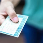 inadimplente pode perder cnh - Mão masculina segurando titular da Carteira Nacional de Motorista (CNH)