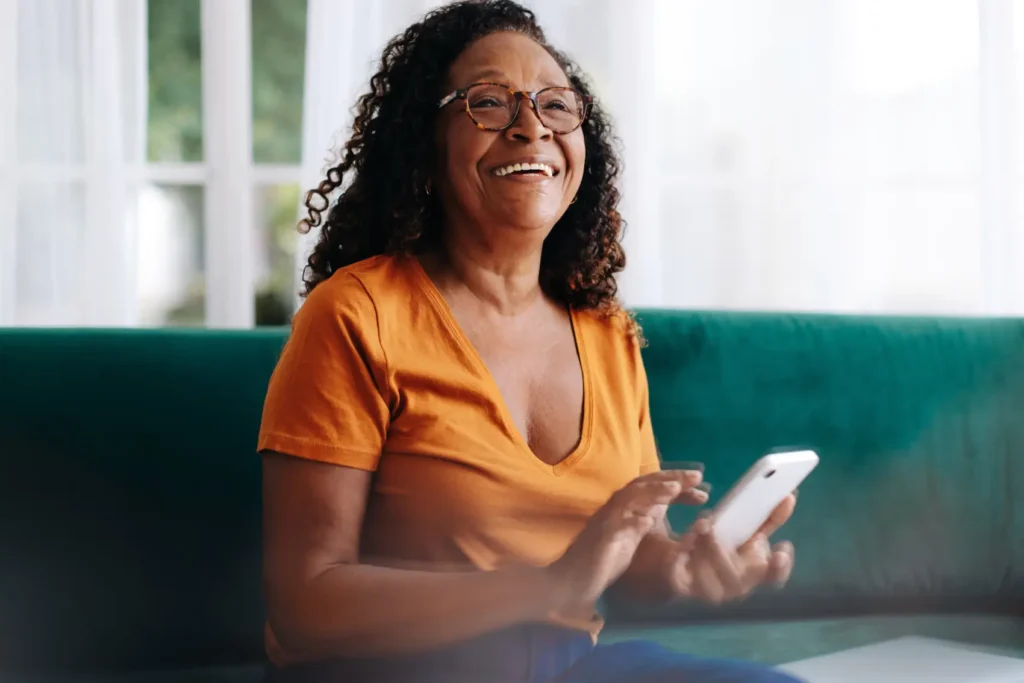 mudancas no consignado inss - idosa negra sorri com celular na mão