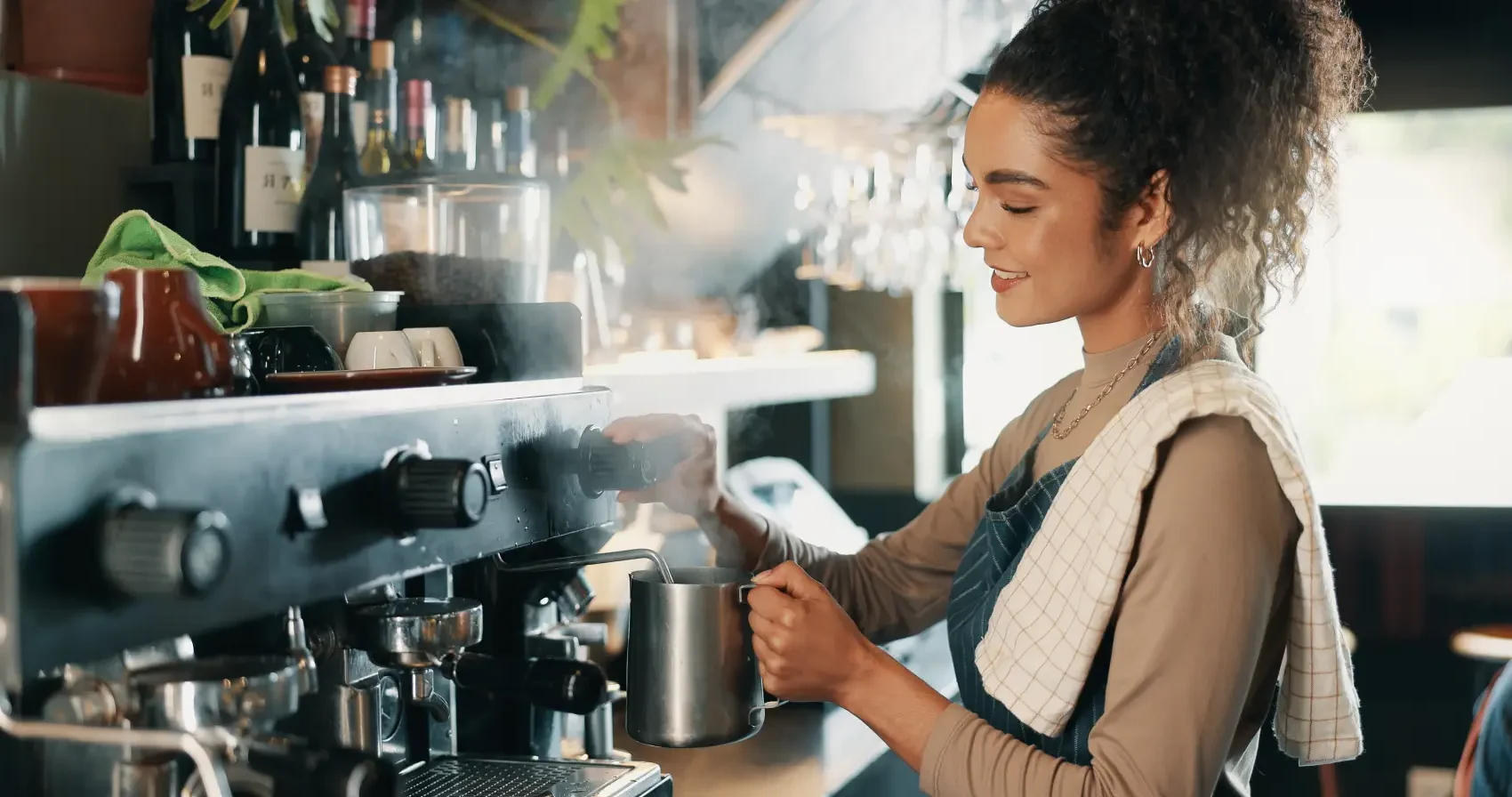 como abrir uma cafeteria​ - mulher barista sorrindo enquanto prepara café na máquina