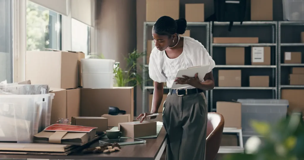 e-commerce-no-brasil - Comércio eletrônico, caixa e prancheta com mulher negra no armazém para transporte, distribuição e correio