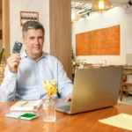 IOF de volta - homem grisalho em frente ao laptop, segurando cartão PagBank