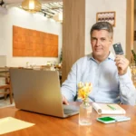 IOF de volta - senhor com cartão do PagBank na mão, em frente ao notebook