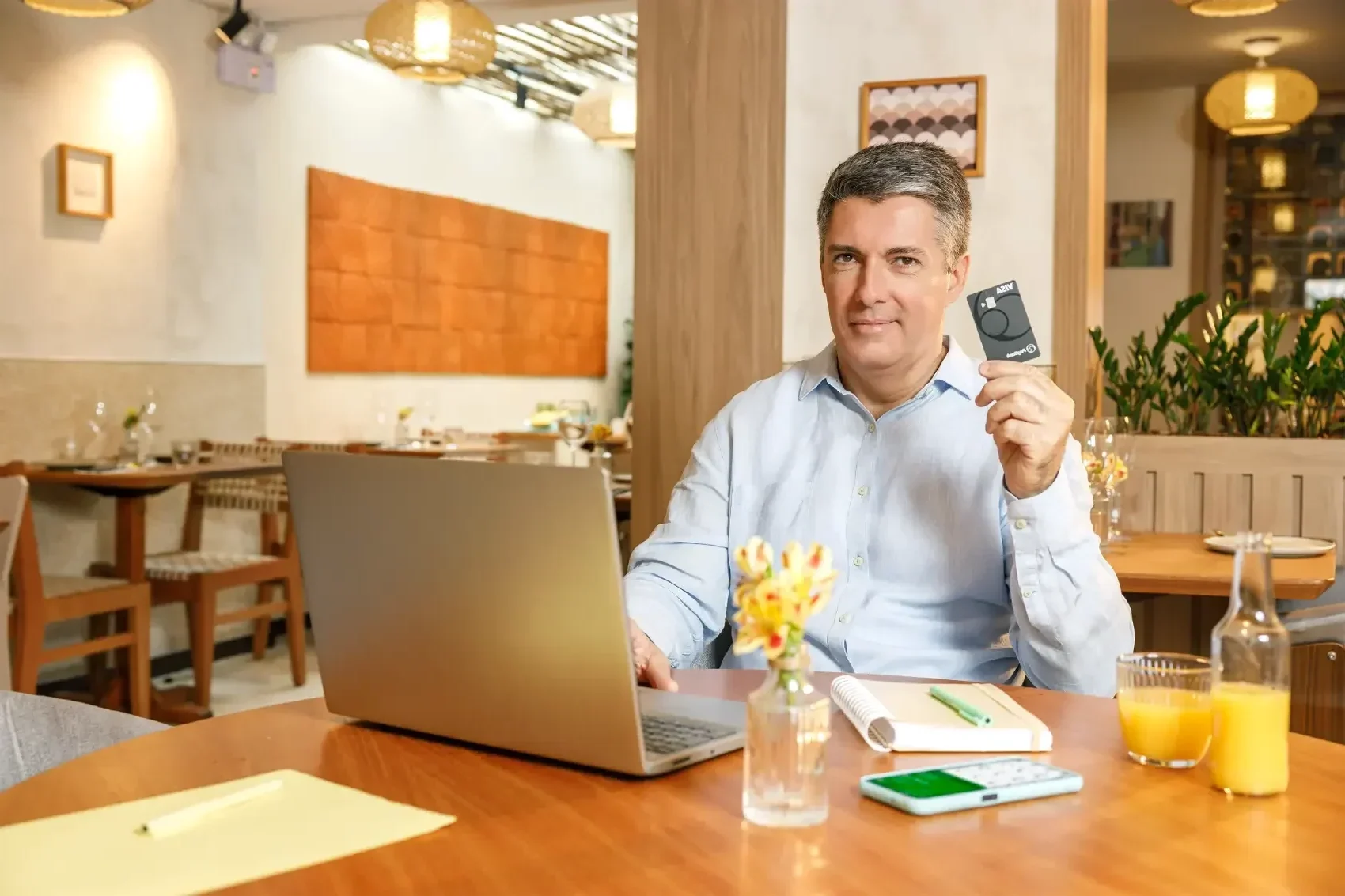 IOF de volta - senhor com cartão do PagBank na mão, em frente ao notebook