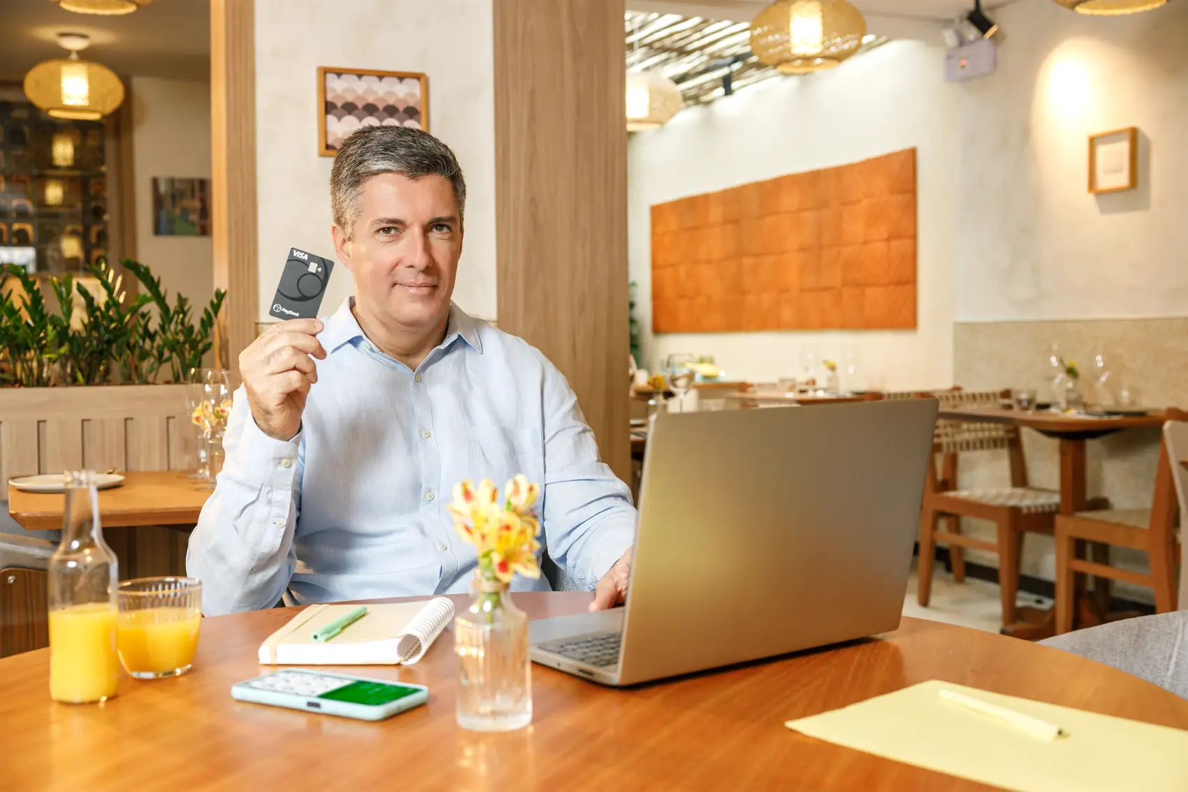 IOF de volta - senhor com cartão do PagBank na mão, em frente ao notebook