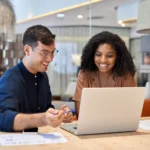 duplicata escritural - Funcionários profissionais da equipe sorridente trabalhando juntos no computador discutindo soluções de dados de tecnologia on-line no trabalho